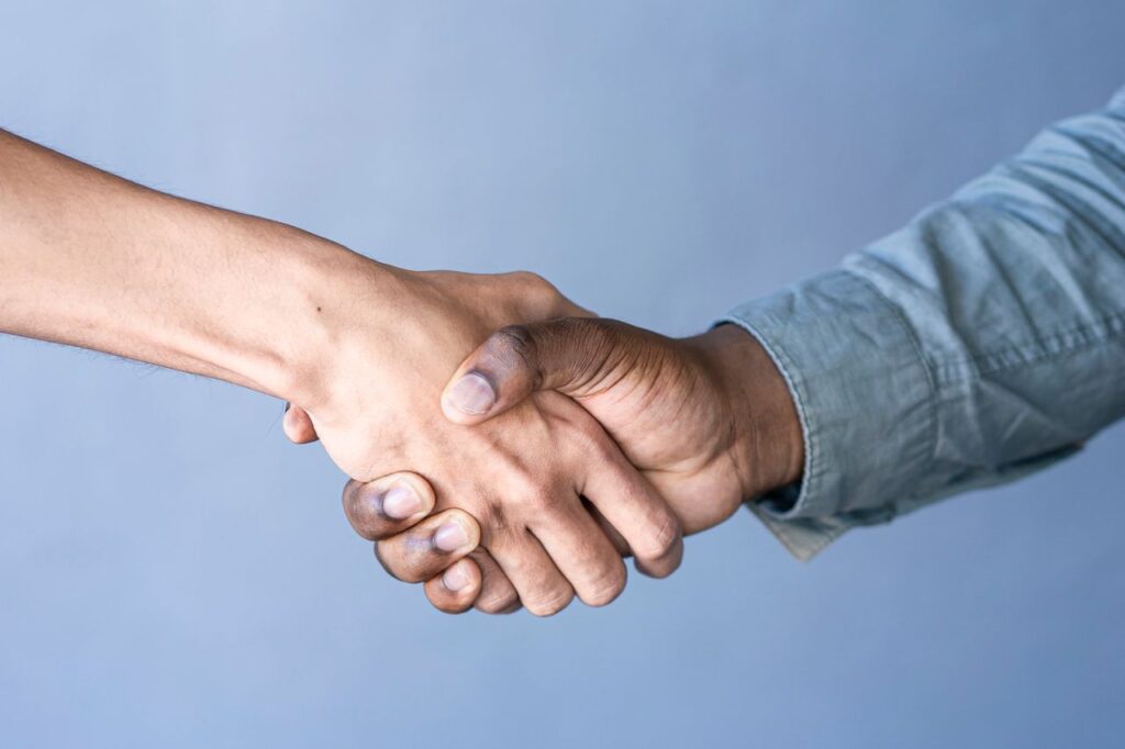 Close-up of a handshake between two people against a blue backdrop.